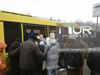 Passengers are getting on a bus that is operating between the closed metro stations of the Blue Line in Kyiv, Ukraine, on December 11, 2023....