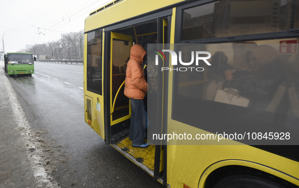 Passengers are getting on a bus that is operating between the closed metro stations of the Blue Line in Kyiv, Ukraine, on December 11, 2023....