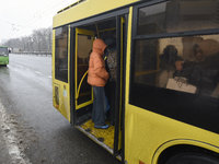 Passengers are getting on a bus that is operating between the closed metro stations of the Blue Line in Kyiv, Ukraine, on December 11, 2023....