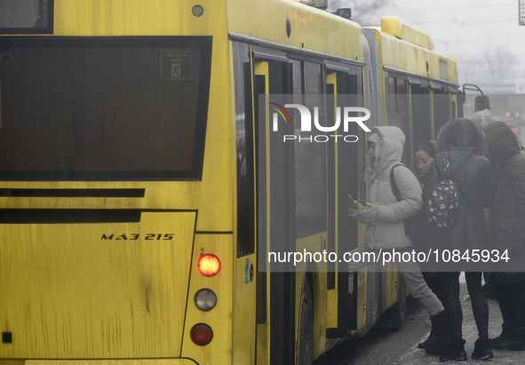 Passengers are getting on a bus that is operating between the closed metro stations of the Blue Line in Kyiv, Ukraine, on December 11, 2023....