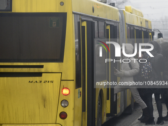 Passengers are getting on a bus that is operating between the closed metro stations of the Blue Line in Kyiv, Ukraine, on December 11, 2023....