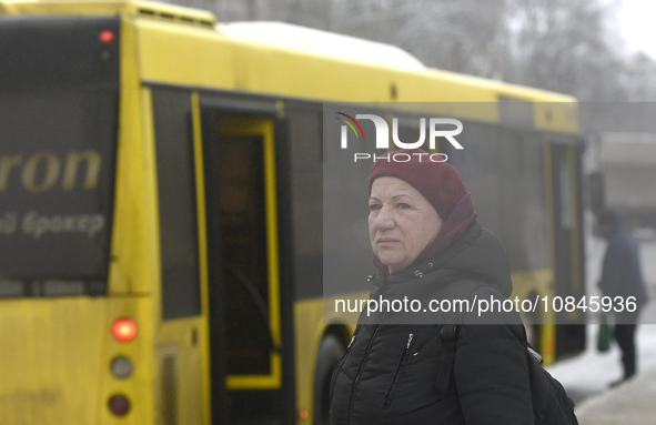 A woman is standing at a stop in Kyiv, Ukraine, on December 11, 2023, as additional buses and trolleybuses are operating between the closed...