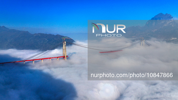 Workers are hoisting a steel girder of the main bridge in the clouds at the Zangke River Bridge on the expressway in Bijie, Guizhou Province...