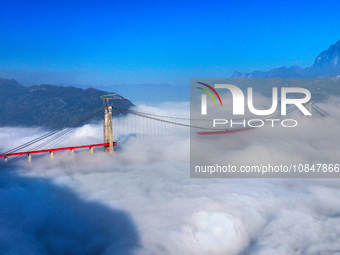 Workers are hoisting a steel girder of the main bridge in the clouds at the Zangke River Bridge on the expressway in Bijie, Guizhou Province...