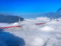 Workers are hoisting a steel girder of the main bridge in the clouds at the Zangke River Bridge on the expressway in Bijie, Guizhou Province...