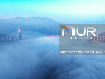 Workers are hoisting a steel girder of the main bridge in the clouds at the Zangke River Bridge on the expressway in Bijie, Guizhou Province...