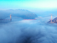 Workers are hoisting a steel girder of the main bridge in the clouds at the Zangke River Bridge on the expressway in Bijie, Guizhou Province...