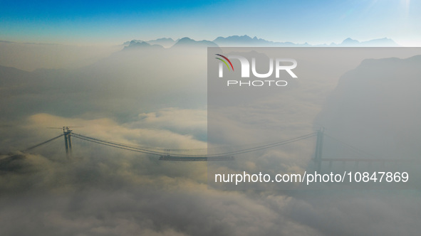 Workers are hoisting a steel girder of the main bridge in the clouds at the Zangke River Bridge on the expressway in Bijie, Guizhou Province...