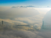 Workers are hoisting a steel girder of the main bridge in the clouds at the Zangke River Bridge on the expressway in Bijie, Guizhou Province...