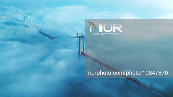 Workers are hoisting a steel girder of the main bridge in the clouds at the Zangke River Bridge on the expressway in Bijie, Guizhou Province...