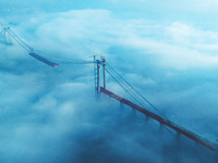 Workers are hoisting a steel girder of the main bridge in the clouds at the Zangke River Bridge on the expressway in Bijie, Guizhou Province...