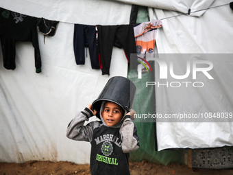 A Palestinian boy is standing amidst the rain at a camp for displaced people in Deir El-Balah, in the central Gaza Strip, where many civilia...