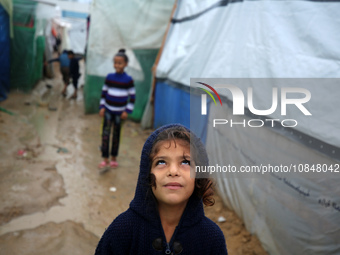 Palestinian children are standing amidst the rain at a camp for displaced people in Deir El-Balah, in the central Gaza Strip, where most civ...