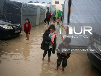 Palestinian children are standing amidst the rain at a camp for displaced people in Deir El-Balah, in the central Gaza Strip, where most civ...