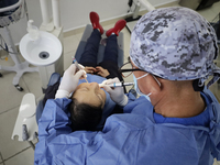 A dentist at the Centro de Salud TIII Doctor Guillermo Roman y Carrillo in the Iztapalapa district of Mexico City is attending to an older a...