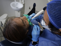 A dentist at the Centro de Salud TIII Doctor Guillermo Roman y Carrillo in the Iztapalapa district of Mexico City is attending to an older a...