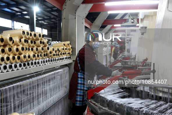 A worker is rushing to complete an order at a woven bag production workshop in Lianyungang, Jiangsu Province, China, on December 15, 2023. 