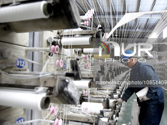 A worker is rushing to complete an order at a woven bag production workshop in Lianyungang, Jiangsu Province, China, on December 15, 2023. (