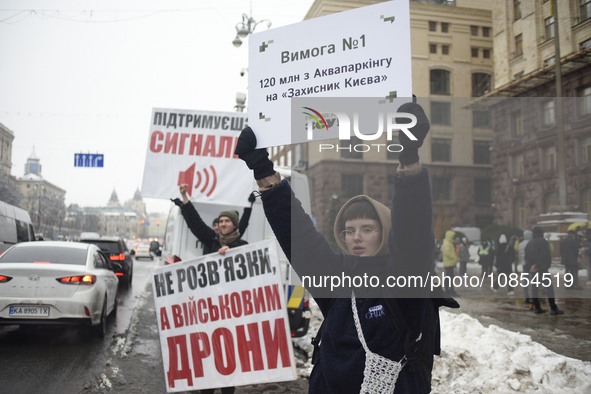 Demonstrators are holding placards as they demand an increase in financial support for the Armed Forces of Ukraine outside the Kyiv City Sta...