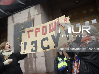 Demonstrators are holding placards as they demand an increase in financial support for the Armed Forces of Ukraine outside the Kyiv City Sta...