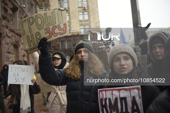 Demonstrators are holding placards as they demand an increase in financial support for the Armed Forces of Ukraine outside the Kyiv City Sta...