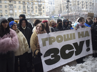 Demonstrators are holding placards as they demand an increase in financial support for the Armed Forces of Ukraine outside the Kyiv City Sta...