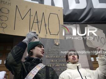 Demonstrators are holding placards as they demand an increase in financial support for the Armed Forces of Ukraine outside the Kyiv City Sta...