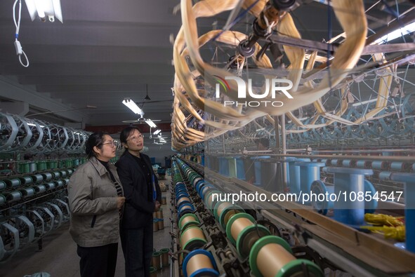 Bank staff are learning about the use of loan funds in the workshop of a textile enterprise in Haian, Jiangsu Province, China, on December 1...