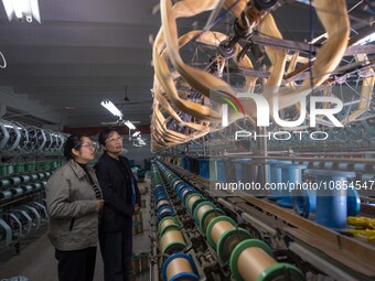 Bank staff are learning about the use of loan funds in the workshop of a textile enterprise in Haian, Jiangsu Province, China, on December 1...