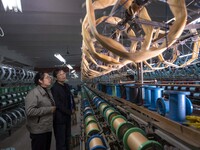 Bank staff are learning about the use of loan funds in the workshop of a textile enterprise in Haian, Jiangsu Province, China, on December 1...