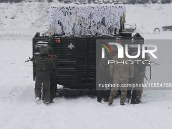 Servicemen are taking cover behind an APC while senior sergeants from the units of the Eastern Operational and Territorial Command of the Na...