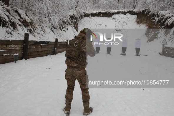 A serviceman is pointing a rifle at a target at a shooting range while senior sergeants from the units of the Eastern Operational and Territ...