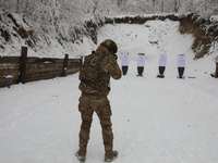 A serviceman is pointing a rifle at a target at a shooting range while senior sergeants from the units of the Eastern Operational and Territ...