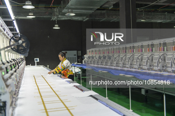 A worker is making embroidery orders at a workshop of a textile enterprise in Congjiang County, Guizhou Province, China, on December 15, 202...