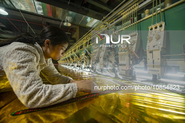 A worker is making embroidery orders at a workshop of a textile enterprise in Congjiang County, Guizhou Province, China, on December 15, 202...