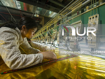 A worker is making embroidery orders at a workshop of a textile enterprise in Congjiang County, Guizhou Province, China, on December 15, 202...