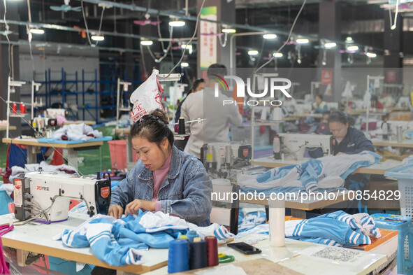 Workers are making an order at a workshop of a clothing company in Congjiang County, Southwest China's Guizhou Province, on December 15, 202...