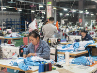 Workers are making an order at a workshop of a clothing company in Congjiang County, Southwest China's Guizhou Province, on December 15, 202...