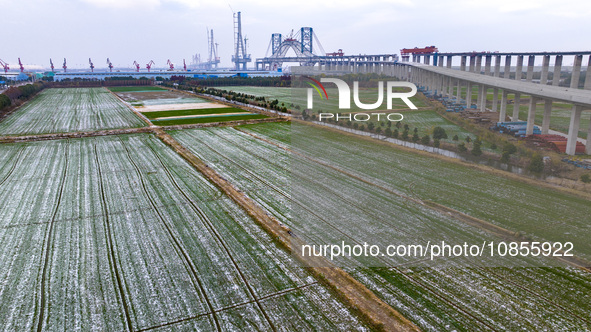 Builders are working in the snow at the construction site of the Changtai Yangtze River Bridge in Taixing, Jiangsu Province, East China, on...