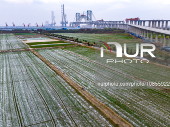 Builders are working in the snow at the construction site of the Changtai Yangtze River Bridge in Taixing, Jiangsu Province, East China, on...