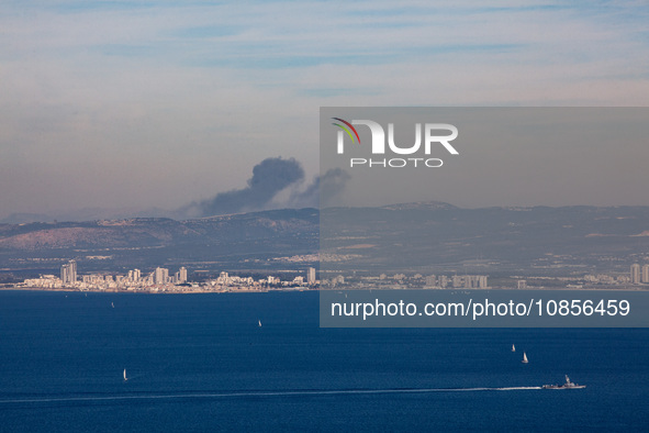 Clouds of smoke are billowing from Israel's northern port city of Haifa on the Mediterranean Coast, and an Israeli naval warship is sailing...