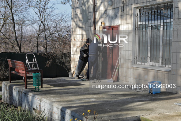 Men are standing outside a building damaged by Russian shelling in Odesa Region, southern Ukraine, on December 17, 2023. 