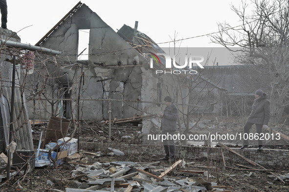 People are standing outside a house that has been damaged by Russian shelling in the Odesa Region, southern Ukraine, on December 17, 2023. 