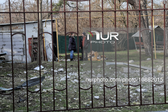 People are standing by a building damaged by Russian shelling in Odesa Region, southern Ukraine, on December 17, 2023. 