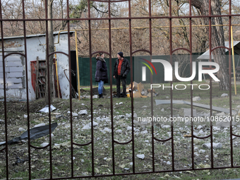 People are standing by a building damaged by Russian shelling in Odesa Region, southern Ukraine, on December 17, 2023. (