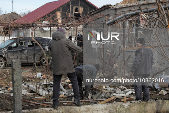 People are standing outside a house that has been damaged by Russian shelling in the Odesa Region, southern Ukraine, on December 17, 2023. 