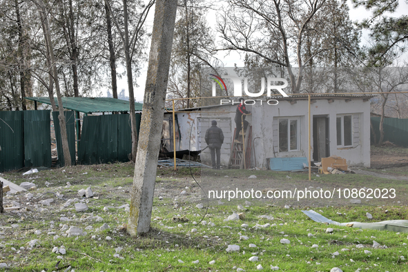 Men are standing by a building damaged by Russian shelling in the Odesa Region, southern Ukraine, on December 17, 2023. 