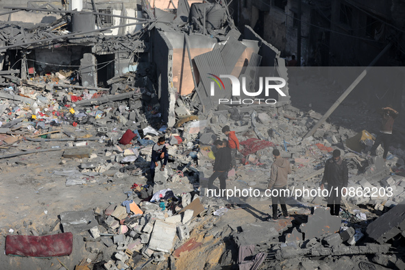 Palestinians are gathering amid the rubble of destroyed buildings following an Israeli bombardment in Deir El-Balah, in the central Gaza Str...