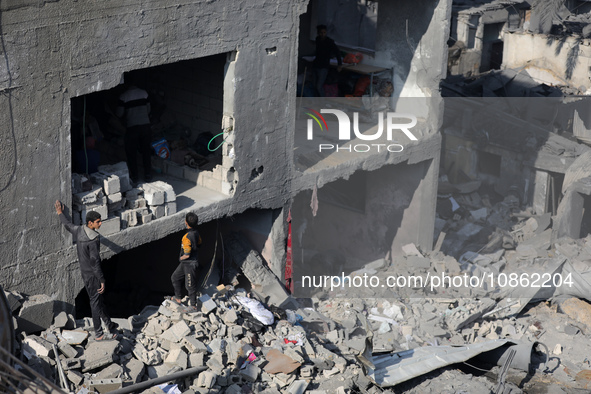 Palestinians are gathering amid the rubble of destroyed buildings following an Israeli bombardment in Deir El-Balah, in the central Gaza Str...