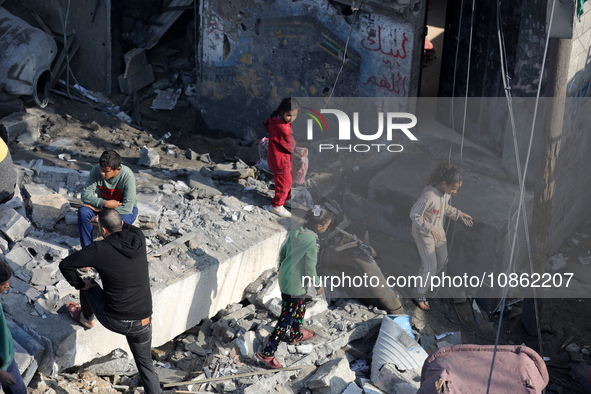 Palestinians are gathering amid the rubble of destroyed buildings following an Israeli bombardment in Deir El-Balah, in the central Gaza Str...